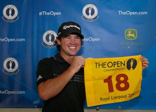 Brian Harman holds up a yellow Open flag