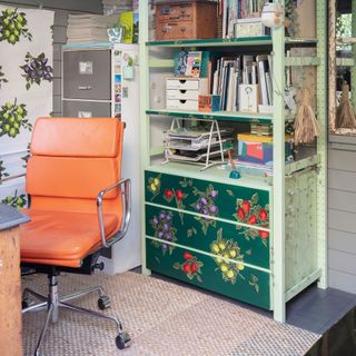 Garden office with orange desk chair, green shelving unit, grey filing cabinet and jute rug