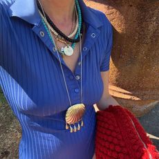 a photo of a woman wearing necklaces and a red bag
