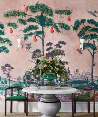 A hallway wallpaper idea with landscape mural with pink sky and round entrance table