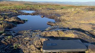 A smartphone lying on a rock with mountains in the background