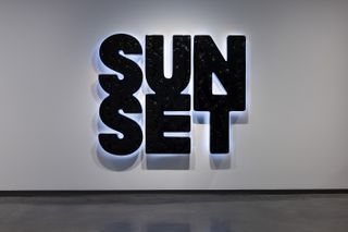 An art installation made out of black material saying SUNSET.