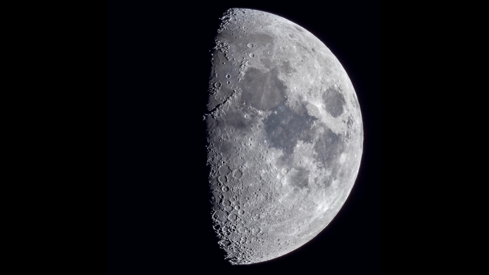 a half-lit moon, showing incredible detail of its craters and mountain ridgelines