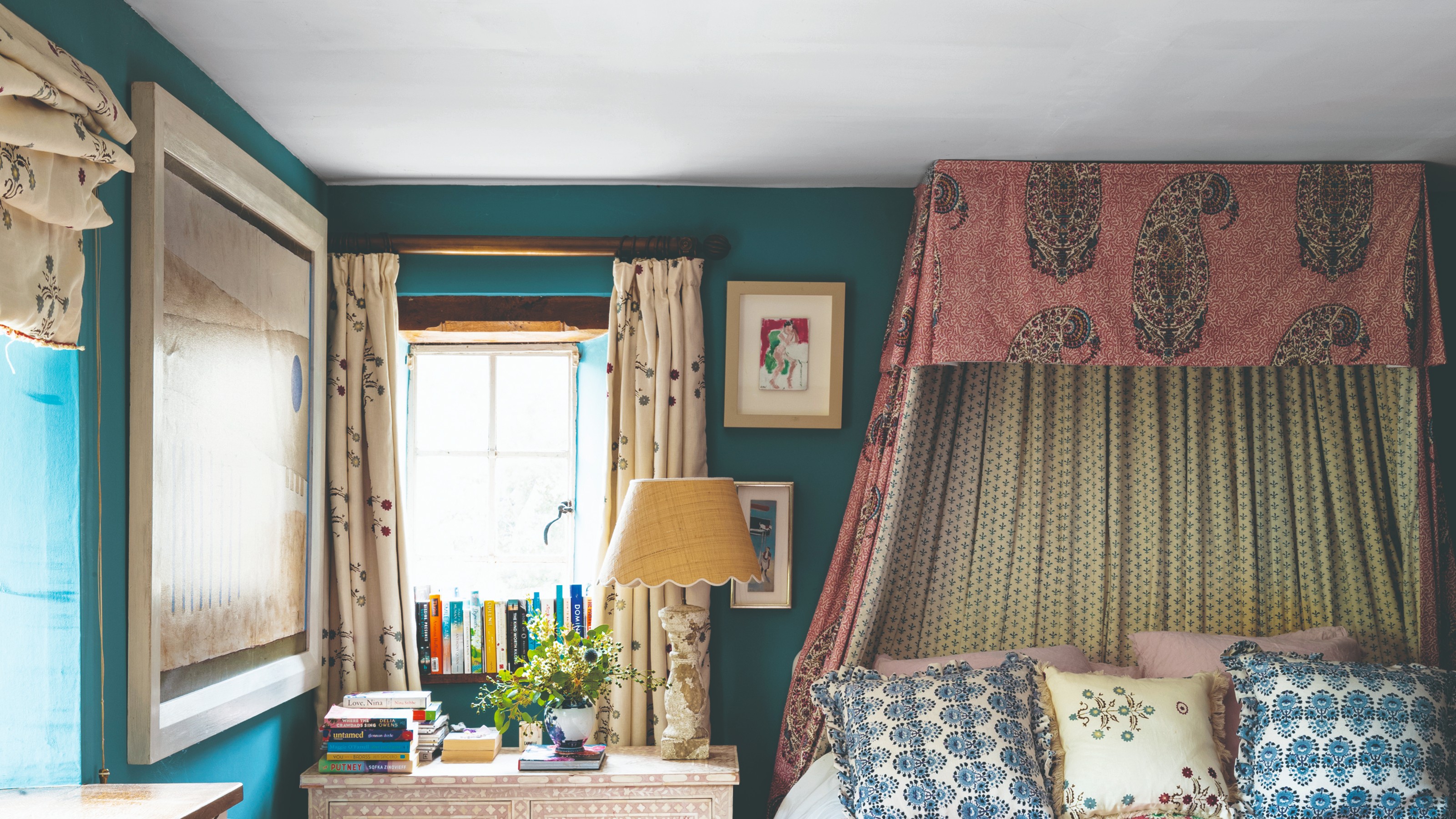 A turquoise-painted bedroom with floral-print curtains and matching Roman blinds dressing the windows