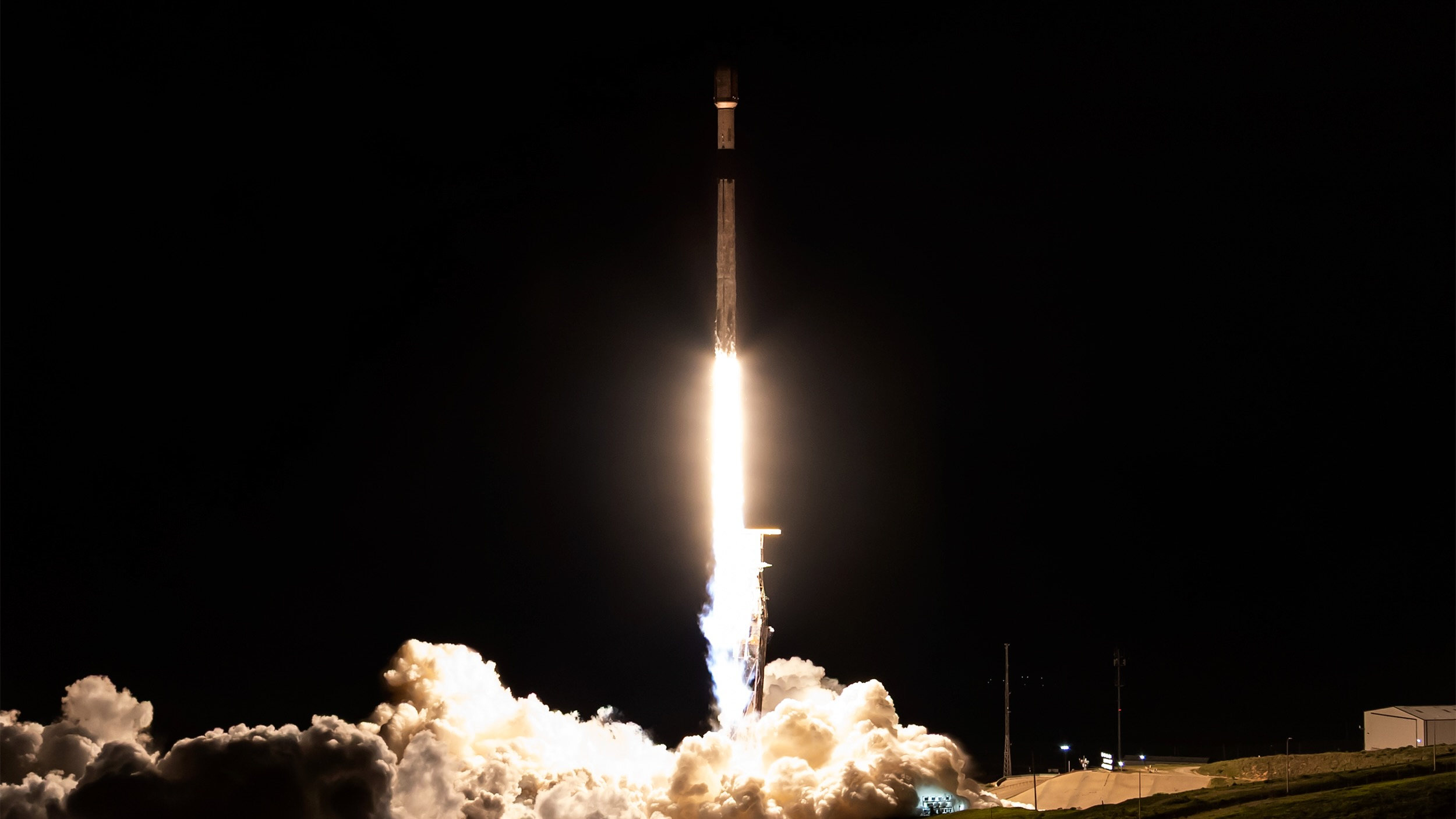 a black-and-white rocket launches into a night sky.