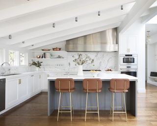 Kitchen with gray island with three bar stools and white kitchen cabinets