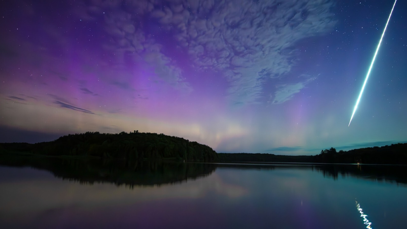 Purple and blue patterns dot the sky over a reflective surface with a streak of light running down the right side