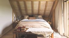 Barn extension decorated with a stylish Scandi feel. Bedroom in attic with wooden walls and double bed. 