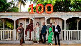 Death in Paradise season 13 cast pose outside the shack with a 100 sign on top