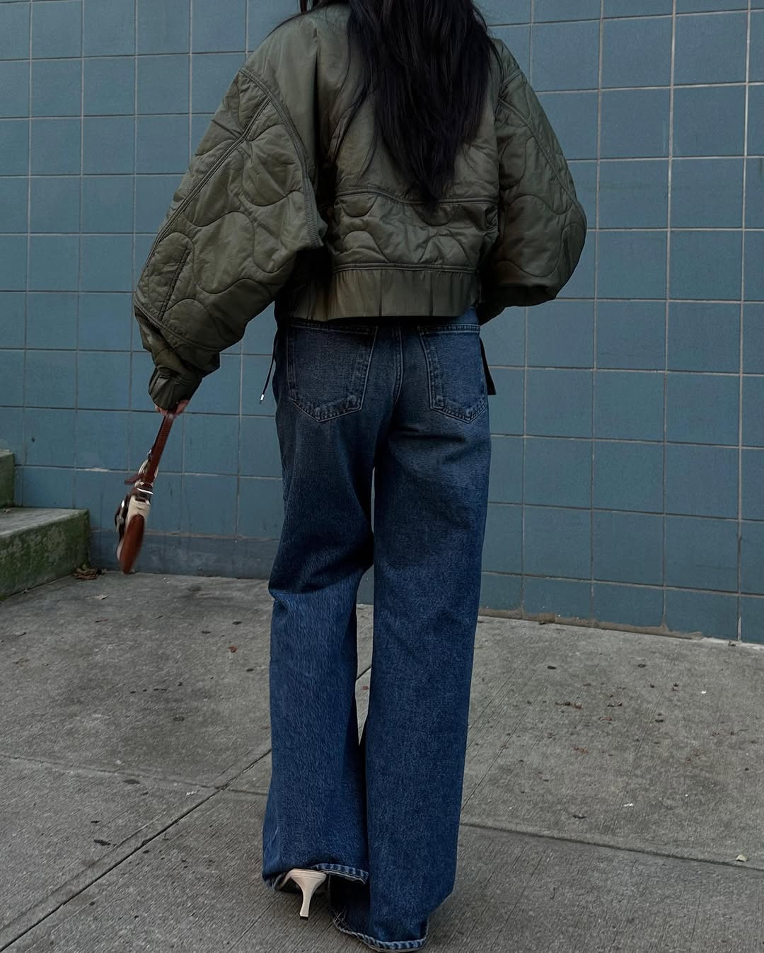 Woman wearing long, baggy jeans fall denim trend 2025.