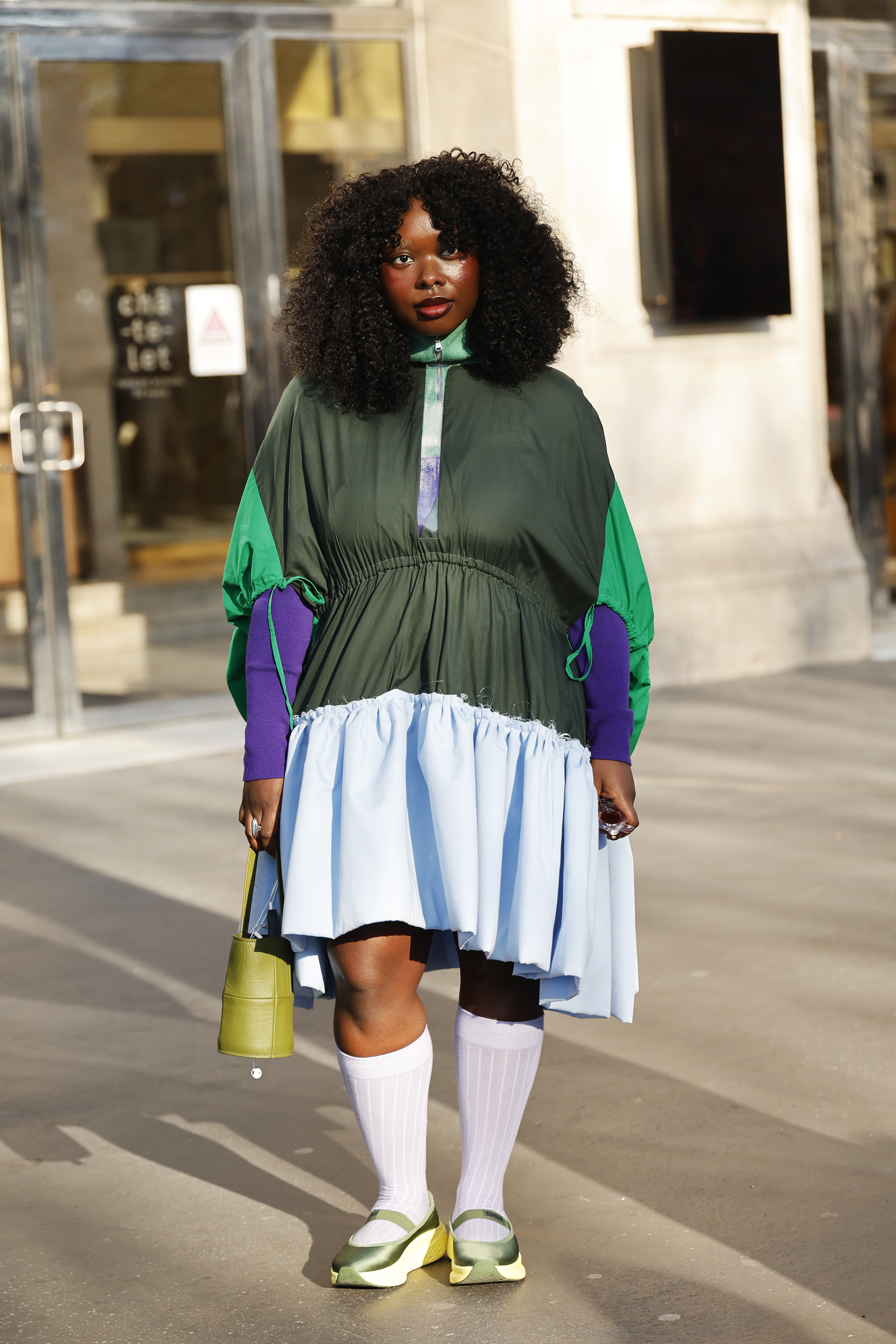 A guest wears a green and light blue dress, purple sweater, white socks, green mary jane sneakers, green bag during Paris Fashion Week - Womenswear Fall 2026 on March 03, 2026 in Paris, France.