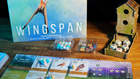 Wingspan box, dice tower, tokens, cards, and board laid out on a wooden table