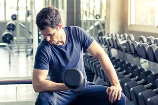 Young man in t-shirt lifting dumbbells in a gym