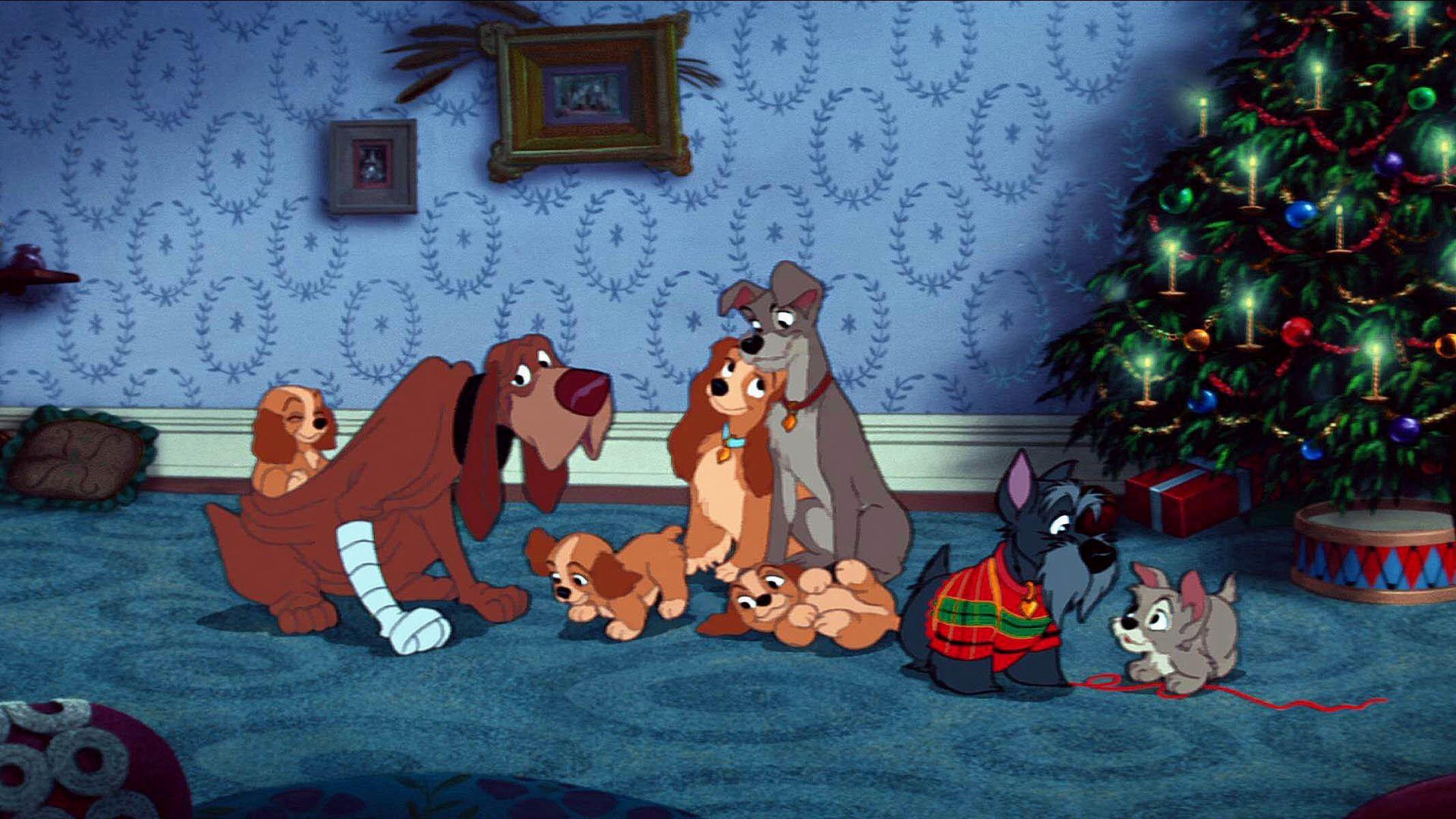 Alt text: Lady, Tramp and their puppies gather with their dog friends in a cosy living room beside a decorated Christmas tree.