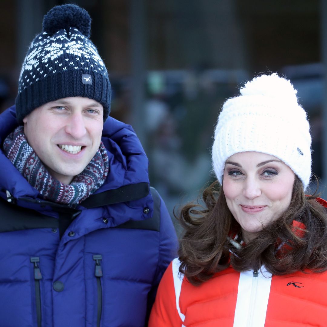 Prince William wearing a blue coat and winter hat and Princess Kate wearing a red coat and white winter hat