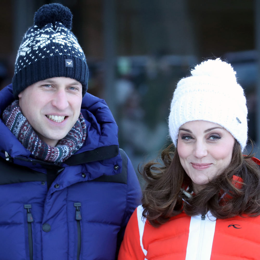 Prince William wearing a blue coat and winter hat and Princess Kate wearing a red coat and white winter hat