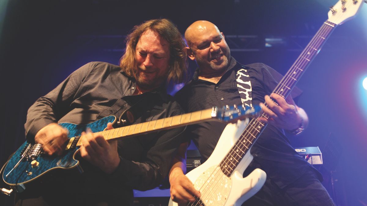 Two guitarists playing live, stood side by side