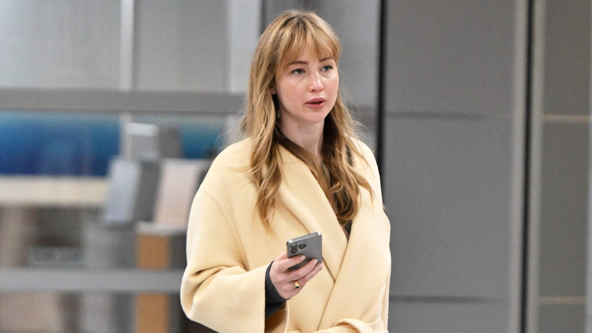 Jennifer Lawrence wearing a yellow coat, black pull-on pants, and Tory Burch Sport Mary Janes