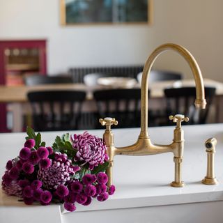 Harvey Jones traditional kitchen close up of brass taps with purple flowers and view into dining area