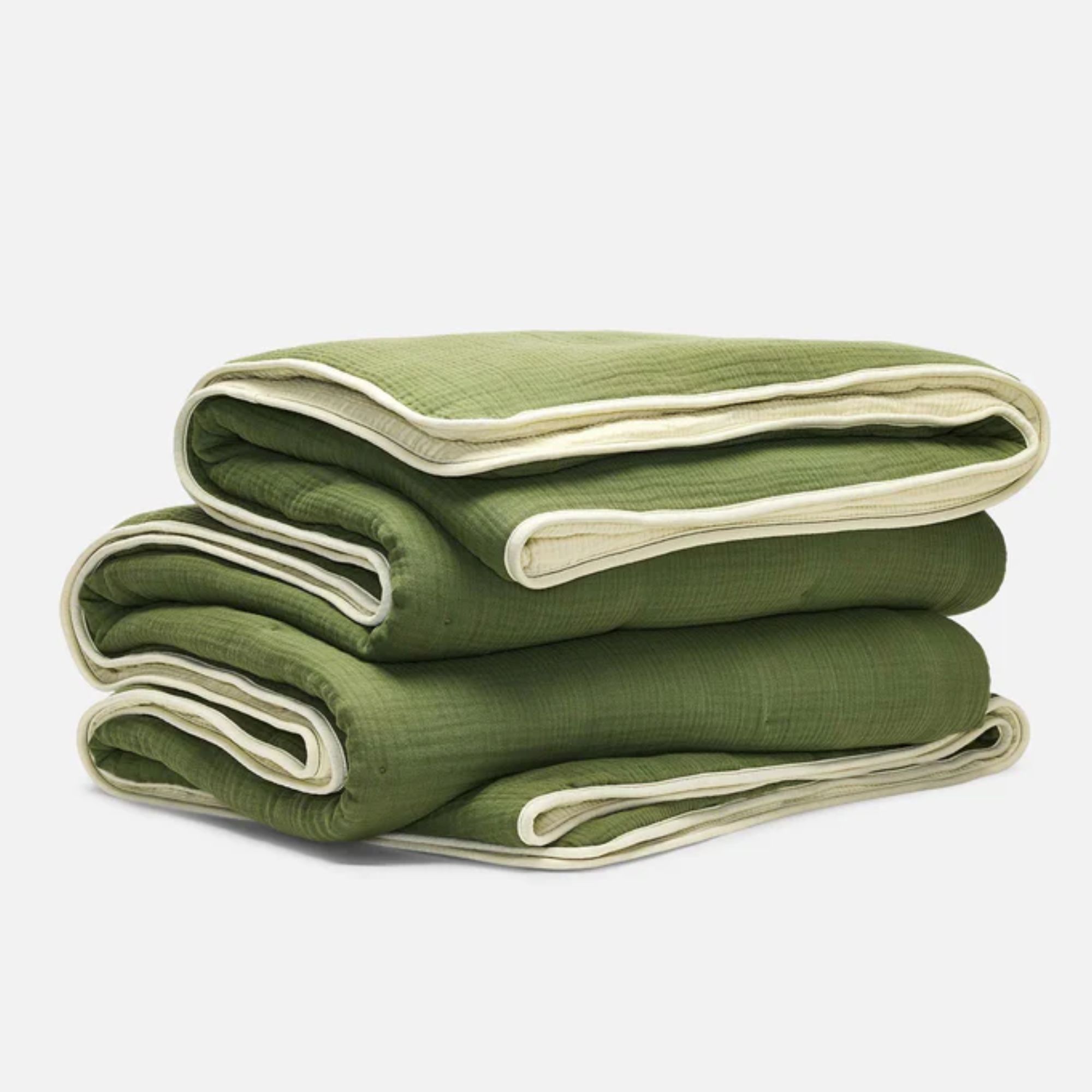 A folded Brooklinen BreezeWeave reversible comforter in green and cream colorway