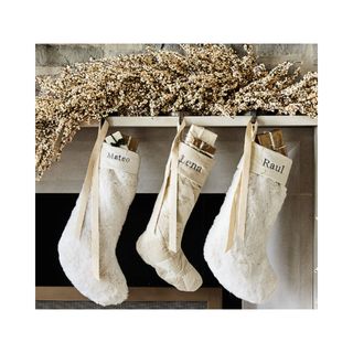 Faux White Mini Berry Garland hanging from a mantle with three white stockings below