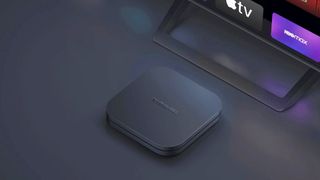 The Xiaomi Mi Box S 2nd Gen sits in front of a TV with Disney+, Apple TV and HBO Max apps displayed