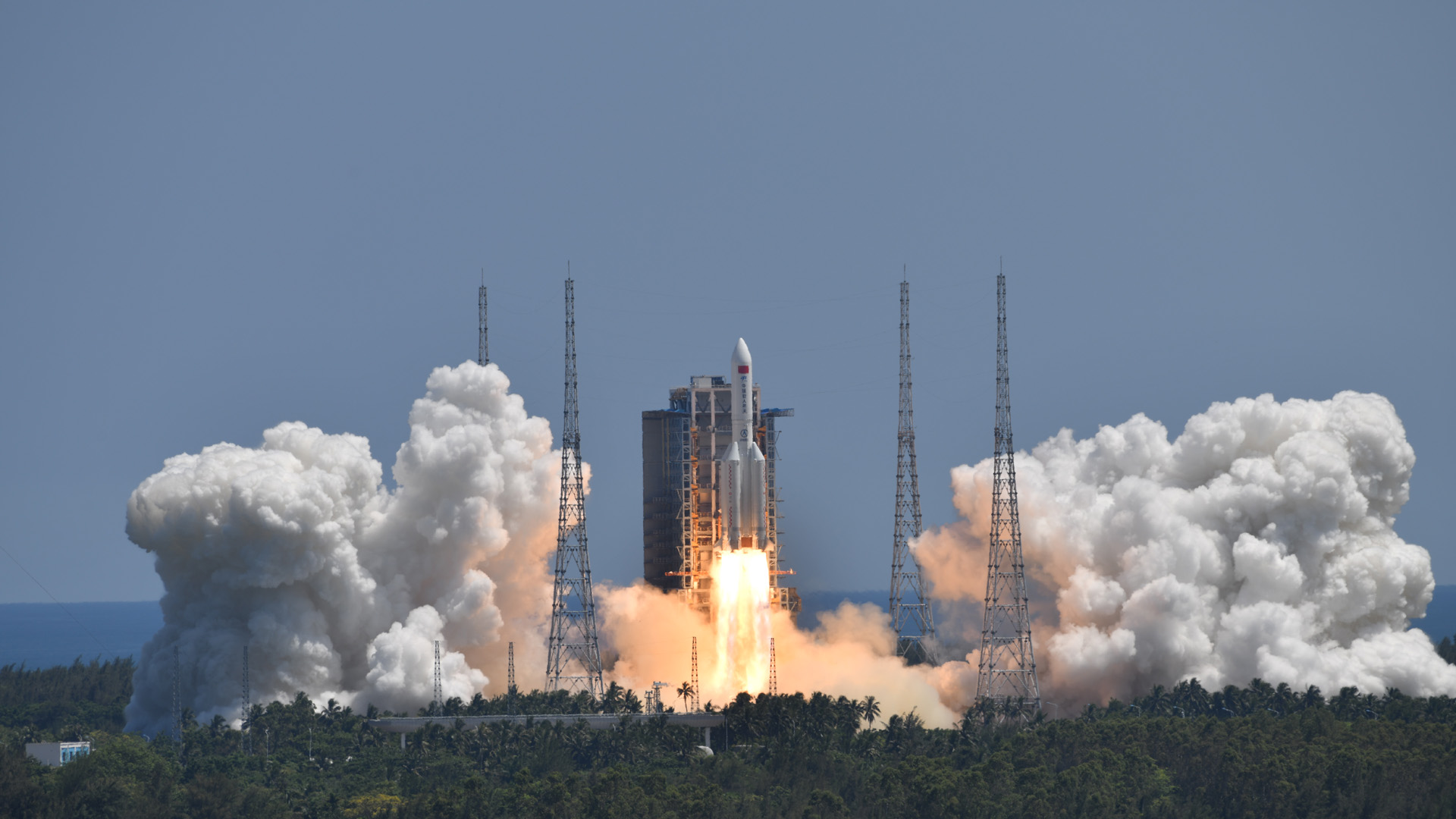 Rocket lifting off from launch pad, billowing clouds surround the area.