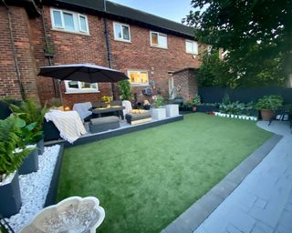 a backyard looking onto the house, with artificial turf and a living area close to the house