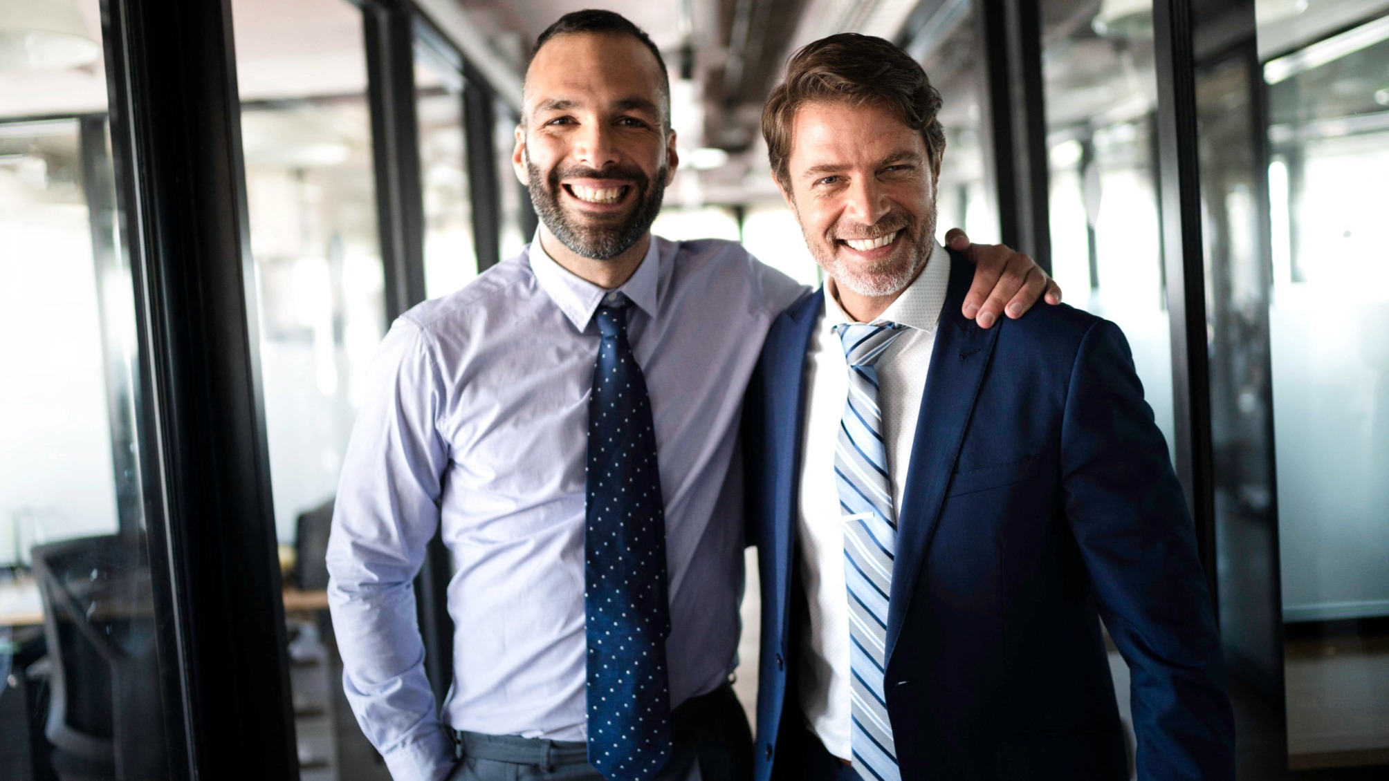 Two young, confident businessmen in an office corridor