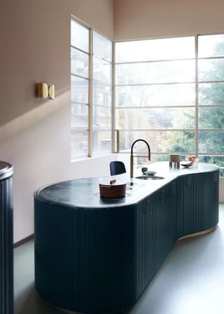 a curvy kitchen island with ribbed doors and a sink.