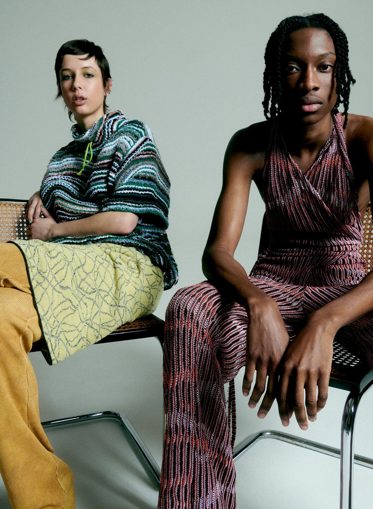 Two people sitting in chairs wearing colourful knitwear pieces by Vitelli