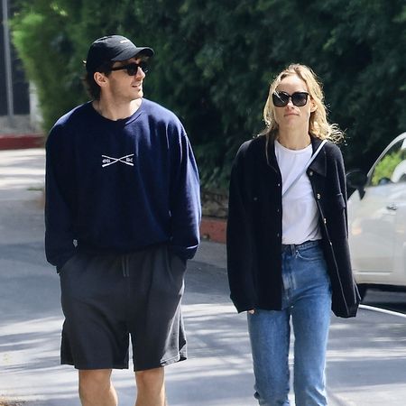 Olivia Wilde wearing a navy shirt, white t-shirt, blue jeans, and yellow sneakers