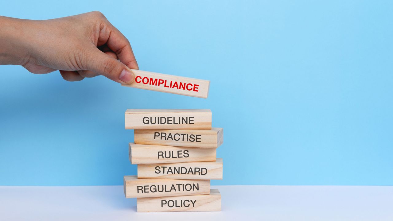 A stack of wooden blocks with the words Compliance, Guideline, Rules, etc. printed on them.