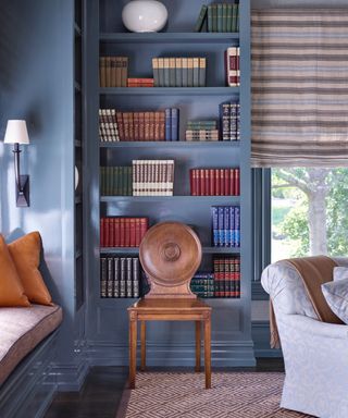 best blue paints, living room with blue painted bookcase, window seat, rug, blind, armchair