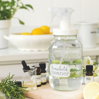 Bottle of homemade household cleaner with bottles of essential oils beside it