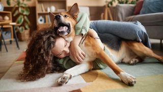 Woman and dog cuddling on the floor