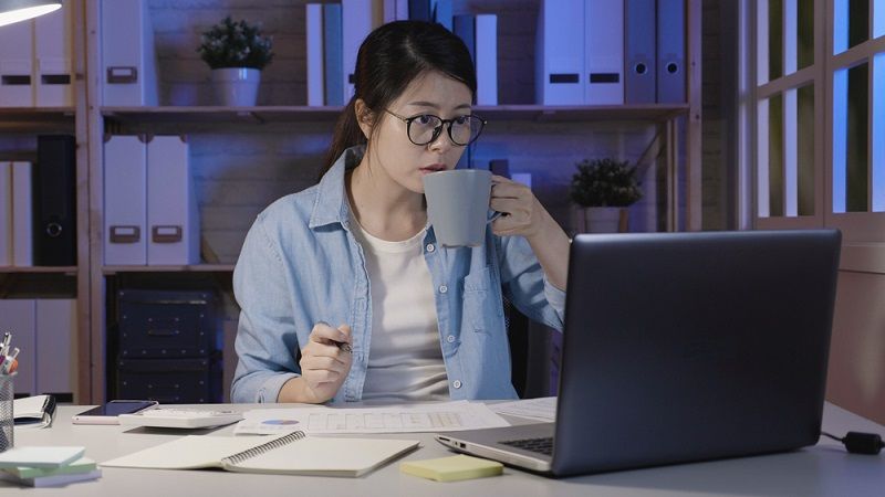 A woman working on her computer at night.