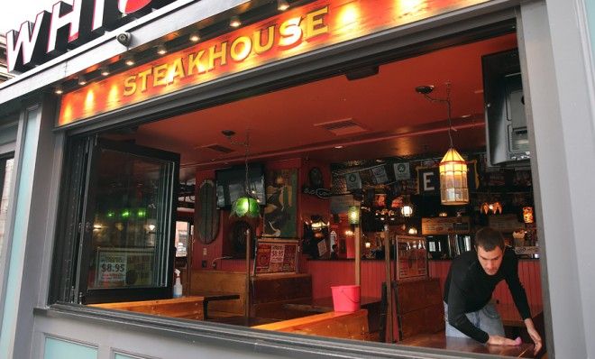 Alec Mikels cleans tables at Whiskey&amp;#039;s Smokehouse on Boylston Street, which is slowly opening back up to the public. 