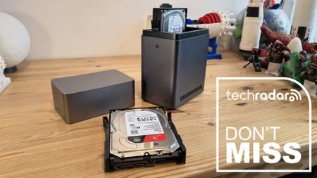 The Ugreen NASync DH2300 on a desk during our testrs with HDDs, a white TechRadar badge in the lower right corner reads 'Don't Miss'