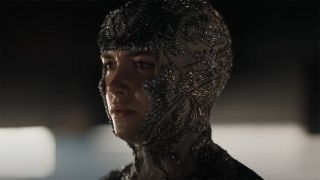 Still from the movie Dune: Part 2. A close up of a person wearing a full headpiece intricately decorated with shiny beads.