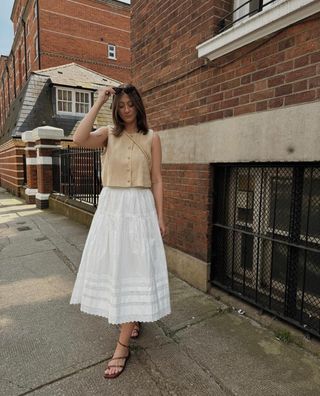 Rachael wears a white full skirt with sandals