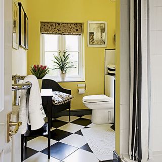 bathroom with yellow wall and back and white tiles floor