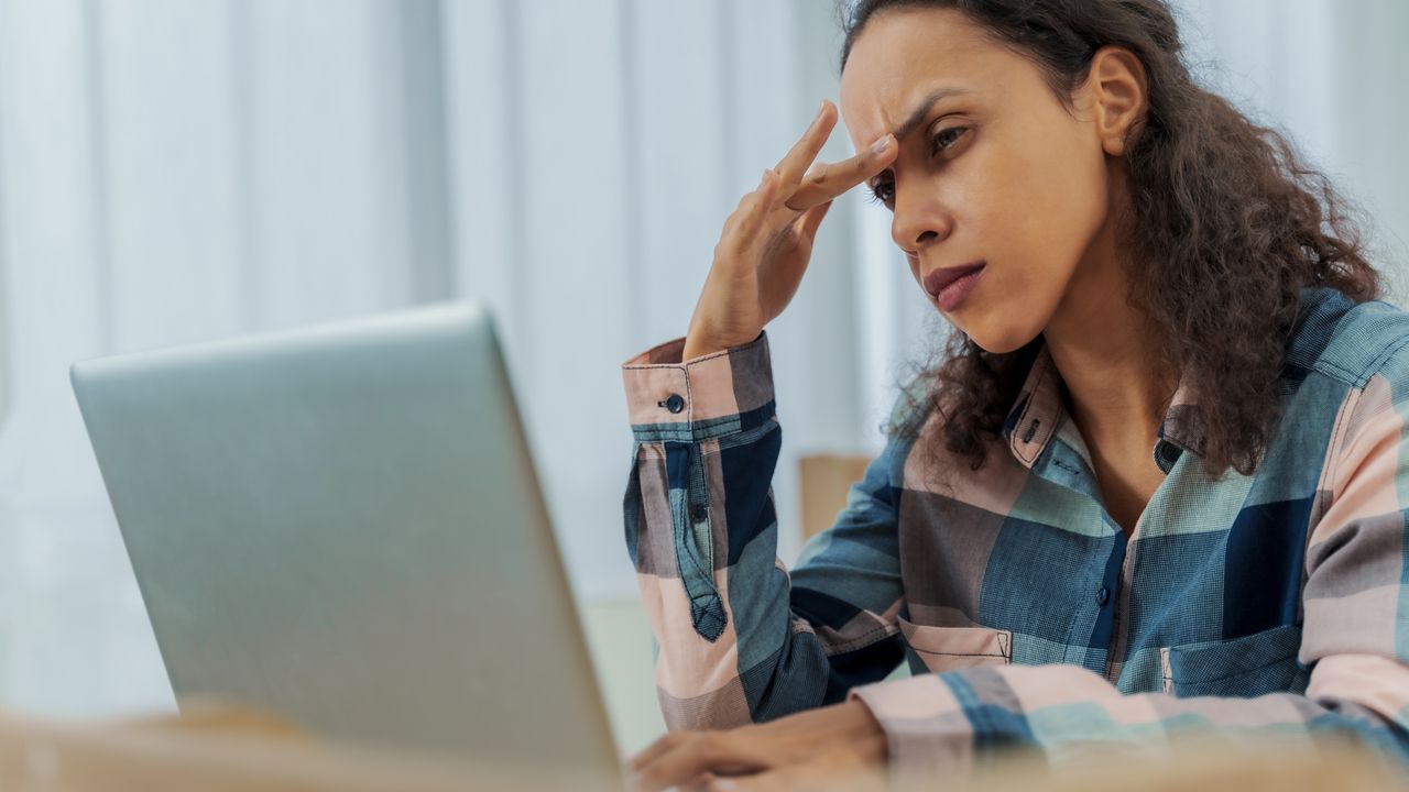 A woman looks frustrated and confused as she looks at her laptop.