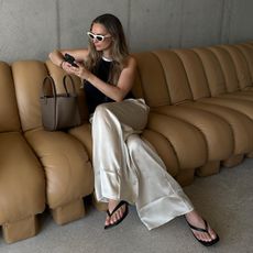 @oliviafaeh wears a pair of cream satin trousers with a black and white vest top