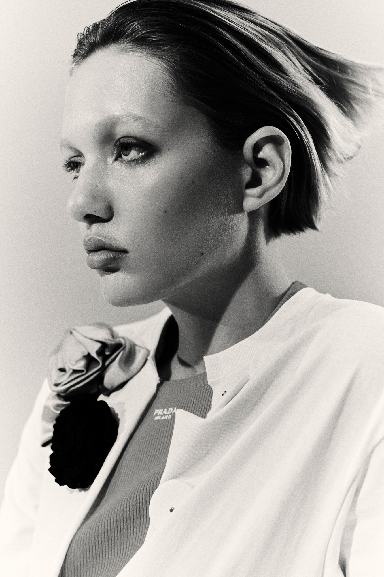 Close up of woman in black and white wearing white shirt with floral adorment by Prada