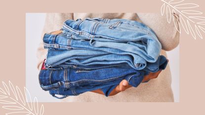 person holding a pile of blue jeans against a plain background to demonstrate how to wash jeans