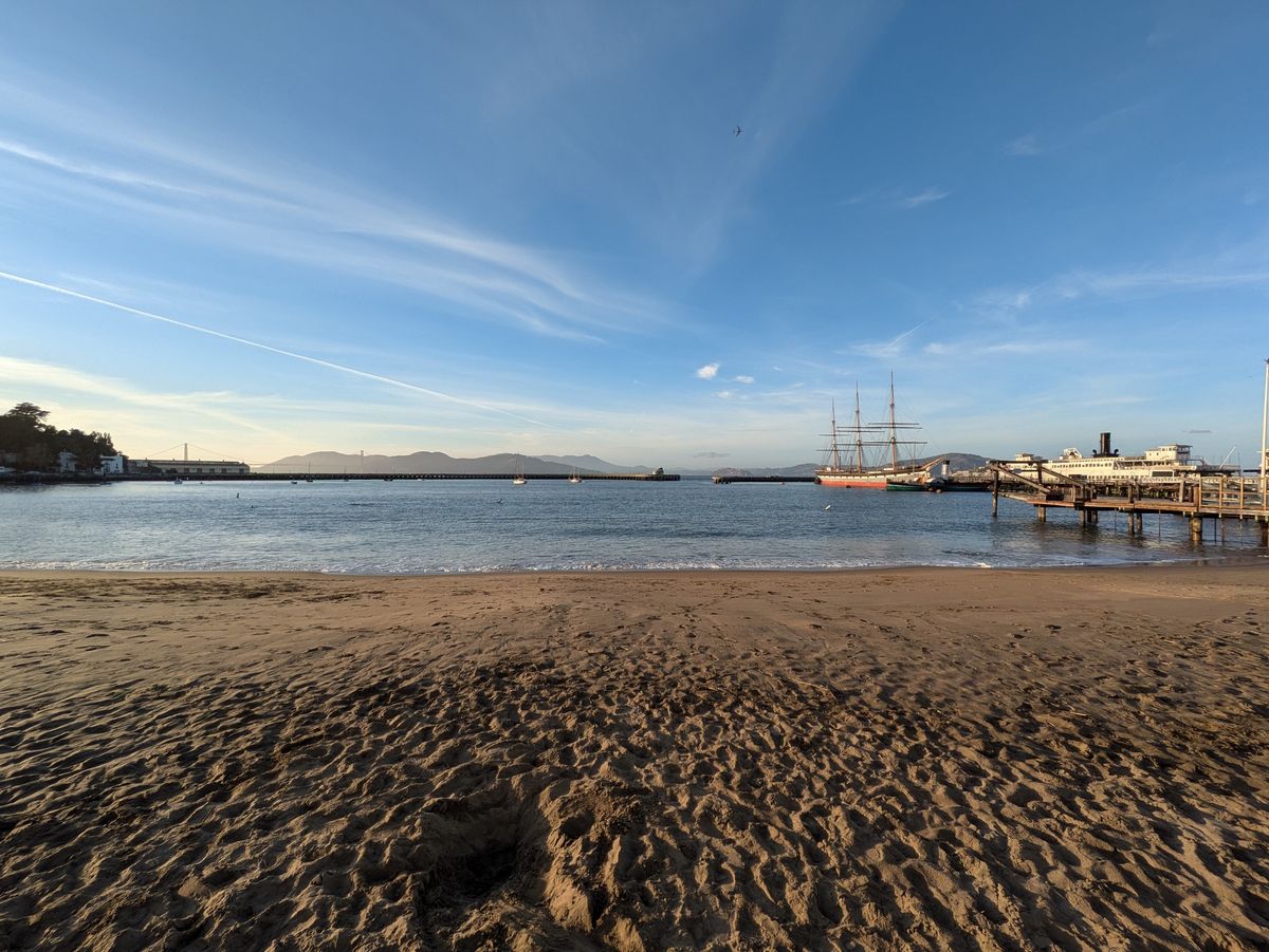 ultrawide photo of beach scene with tall ship in background shot on
