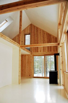 Inside the timber house with timber beams. Large windows at the front and on the upper floor.