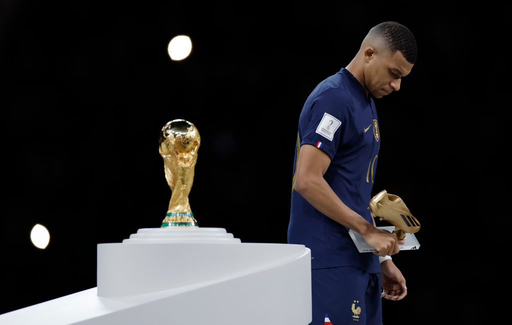 Kylian Mbappe walks past the World Cup trophy with his Golden Boot award in hand