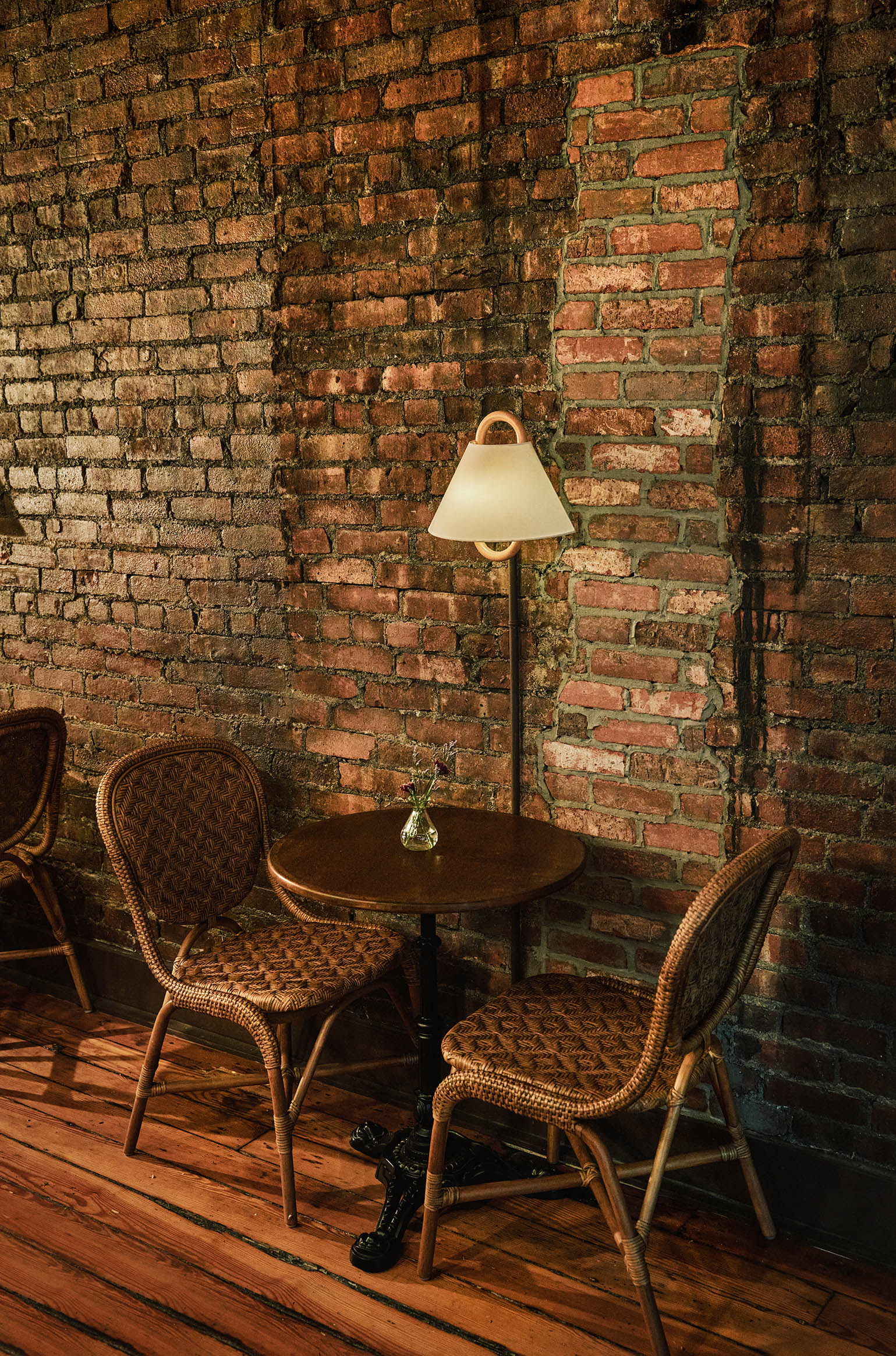 Interior shots of a brick, wood, and marble-clad cafe, bakery, and butcher, decorated with modern rustix furnishings and floral wallpaper.
